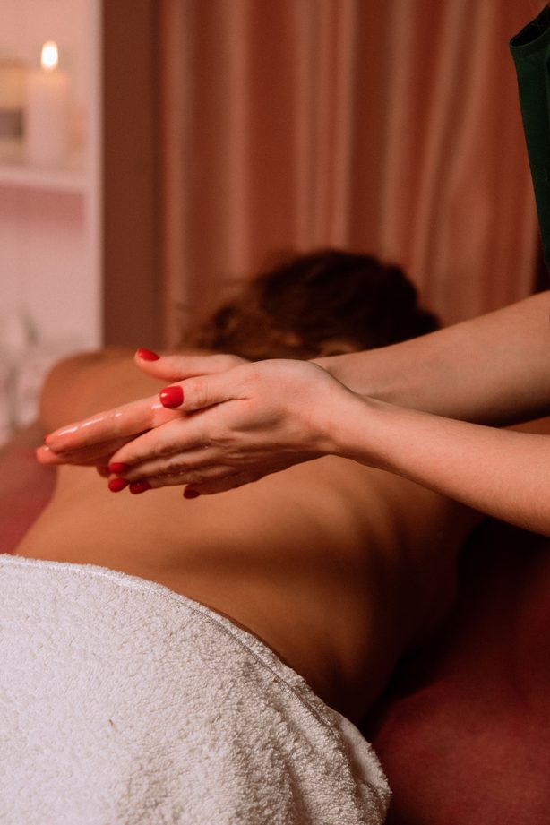 Öl- und Aromaölmassage – Hände tragen warmes Massageöl auf