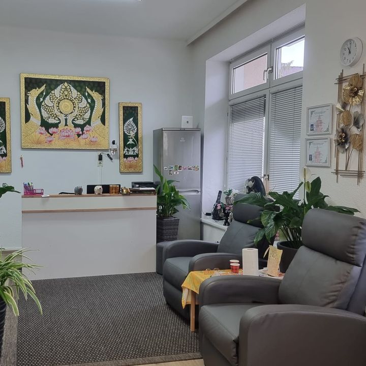 Empfangsbereich mit Theke, thailändischen Wandbildern, Zimmerpflanzen und zwei Ruhesesseln