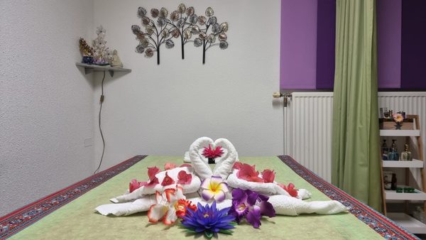 Massageliege mit kunstvoll gefalteten Handtüchern und Blüten