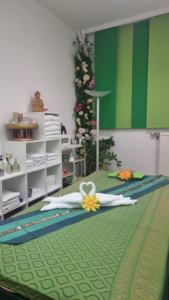 Massageliege im Raum mit grünen Wandpaneelen und Blumendekoration
